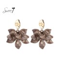Taupe kleurige oorhangers met een grote bloem en goudkleurig oor stukje